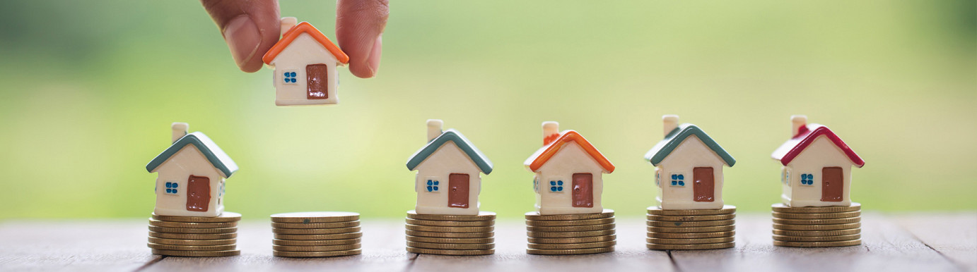 Model houses placed on stacked coins